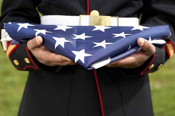 folded U.S. flag held by soldier in uniform