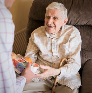 elderly man receives a meal at home thanks to Meals on Wheels