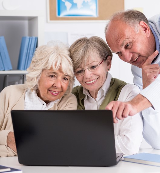 three older adults viewing info on a laptop computer